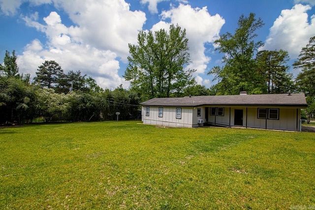 rear view of property featuring board and batten siding, a lawn, and a chimney