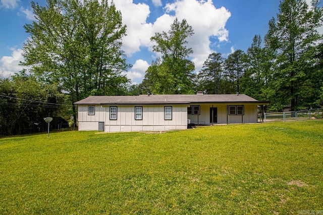 view of front of property featuring board and batten siding, fence, and a front yard