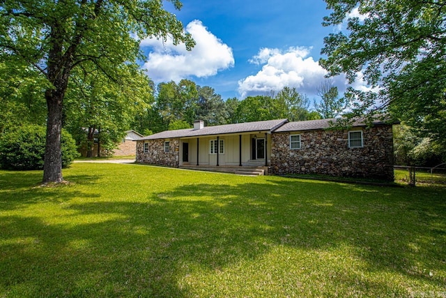 rear view of property with a porch, board and batten siding, a lawn, fence, and stone siding
