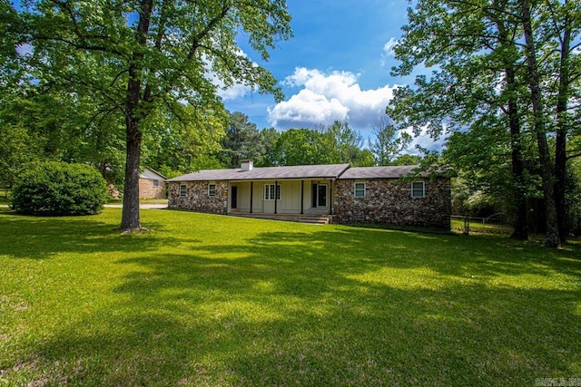 view of front of home featuring a chimney, a front lawn, covered porch, and stone siding