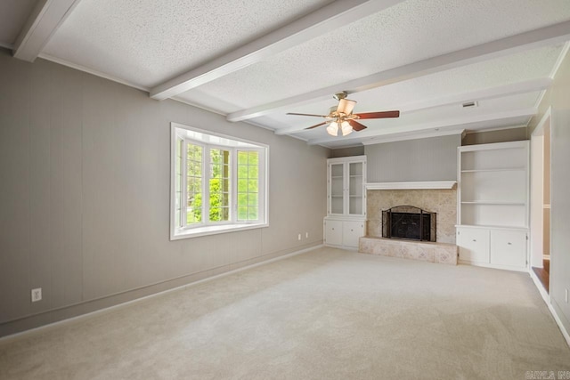unfurnished living room with visible vents, a ceiling fan, beamed ceiling, a fireplace with raised hearth, and carpet flooring