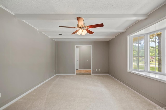 empty room featuring beamed ceiling, a textured ceiling, and light carpet