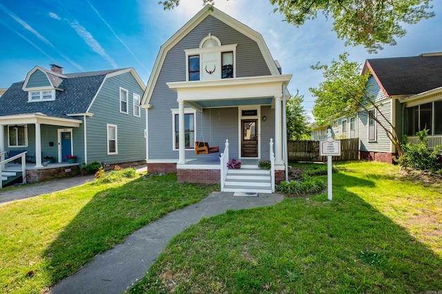 dutch colonial with covered porch, a gambrel roof, and a front yard