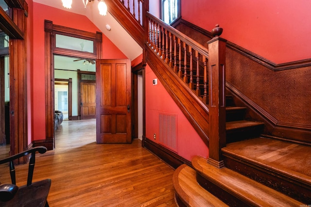 stairs with visible vents, wood finished floors, and an inviting chandelier