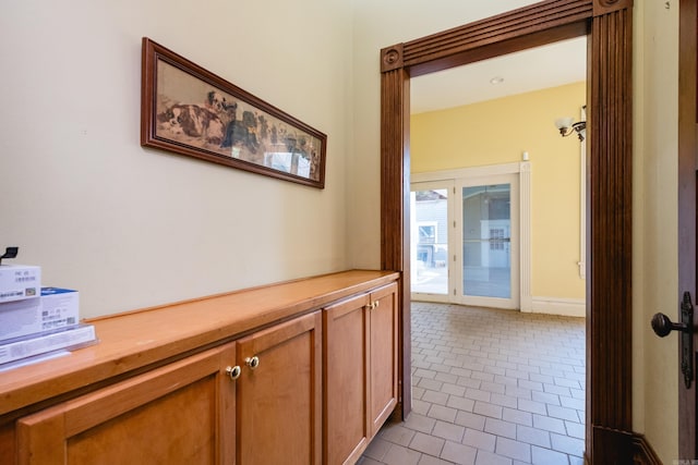 hall featuring baseboards and light tile patterned flooring