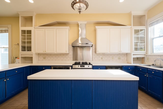 kitchen featuring a kitchen island, blue cabinetry, tasteful backsplash, stainless steel gas range, and wall chimney exhaust hood