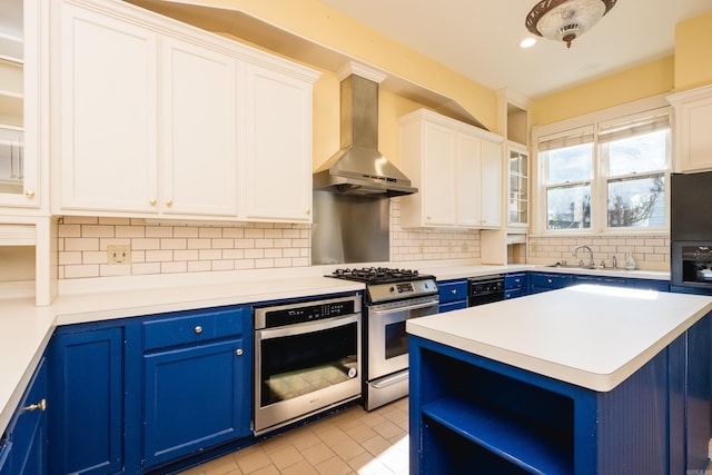 kitchen with wall chimney range hood, appliances with stainless steel finishes, blue cabinetry, and a sink