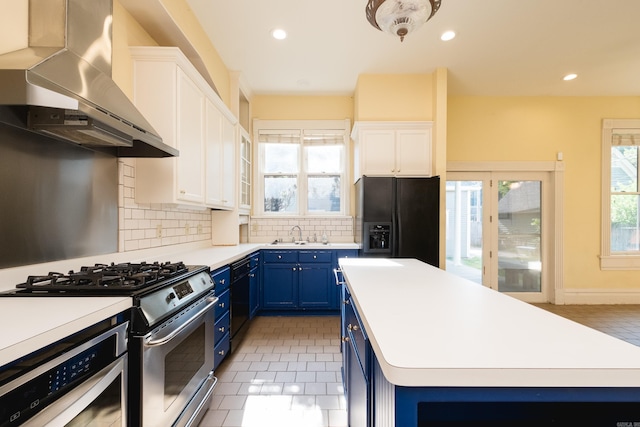 kitchen featuring decorative backsplash, a kitchen island, wall chimney range hood, black appliances, and blue cabinetry