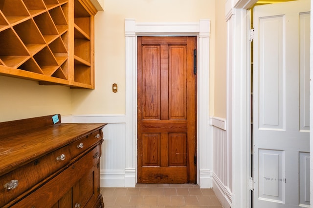 entryway featuring wainscoting, light tile patterned floors, and a decorative wall