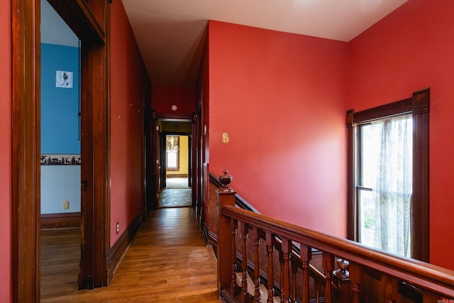 corridor with an upstairs landing and wood finished floors