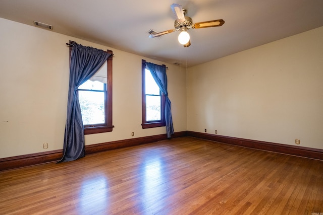 empty room featuring visible vents, baseboards, ceiling fan, and wood finished floors