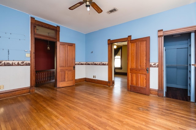 unfurnished room with baseboards, a ceiling fan, light wood finished floors, and visible vents
