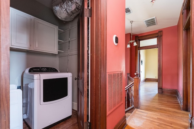 laundry room featuring cabinet space, visible vents, light wood-type flooring, and washing machine and clothes dryer