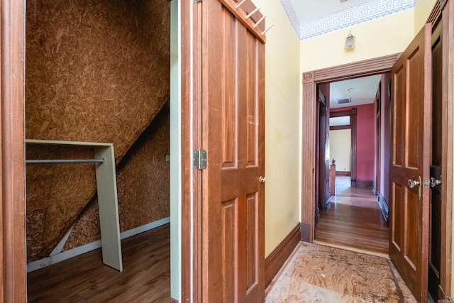 corridor with baseboards, crown molding, wood finished floors, and visible vents
