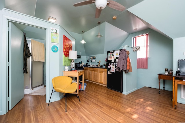 home office featuring a ceiling fan, baseboards, vaulted ceiling, and light wood-style flooring