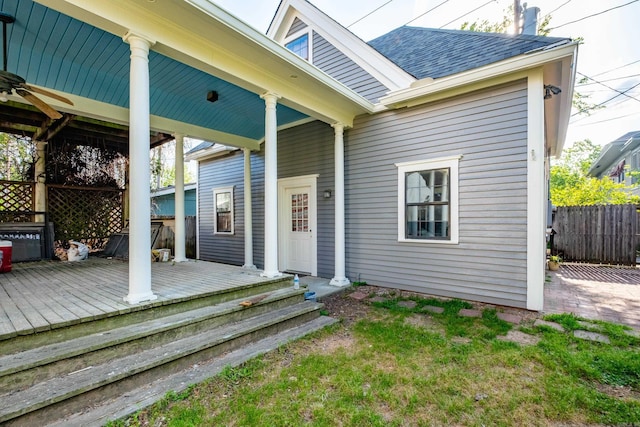 rear view of house with fence, a shingled roof, and a wooden deck