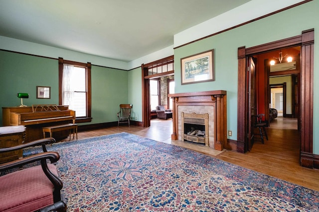 living room with a healthy amount of sunlight, baseboards, a brick fireplace, and wood finished floors