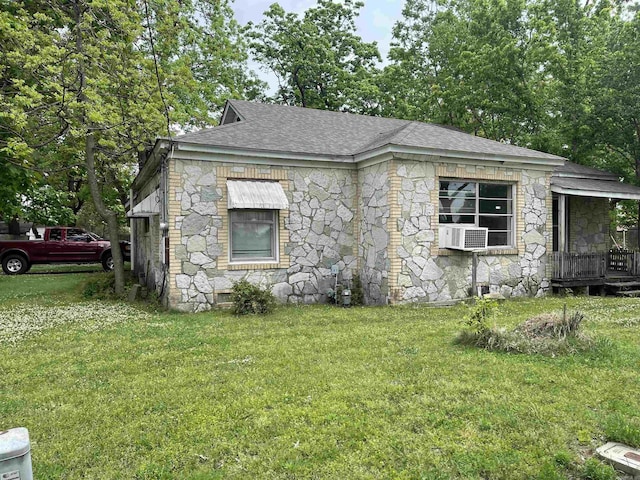 view of front of house featuring cooling unit, a shingled roof, stone siding, and a front lawn