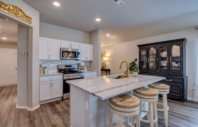 kitchen featuring appliances with stainless steel finishes, a sink, dark wood finished floors, white cabinetry, and visible vents