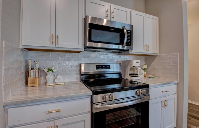 kitchen featuring white cabinets, backsplash, appliances with stainless steel finishes, and light stone counters