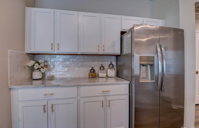 kitchen with backsplash, stainless steel refrigerator with ice dispenser, and white cabinetry