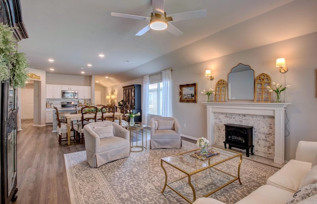 living area with a ceiling fan, wood finished floors, baseboards, lofted ceiling, and recessed lighting