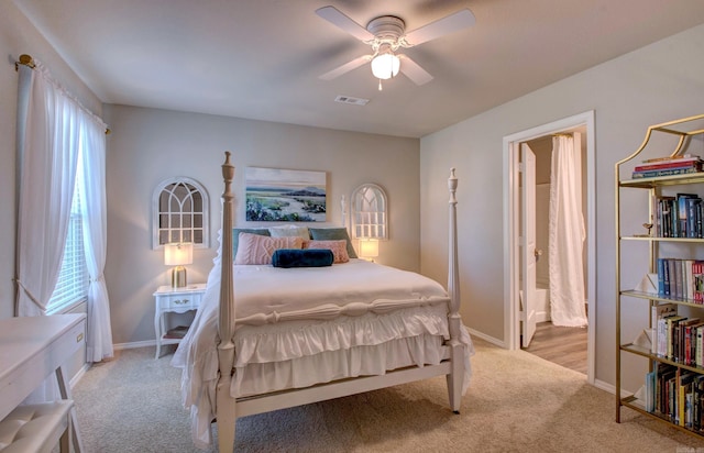 carpeted bedroom featuring baseboards, a ceiling fan, ensuite bath, and visible vents