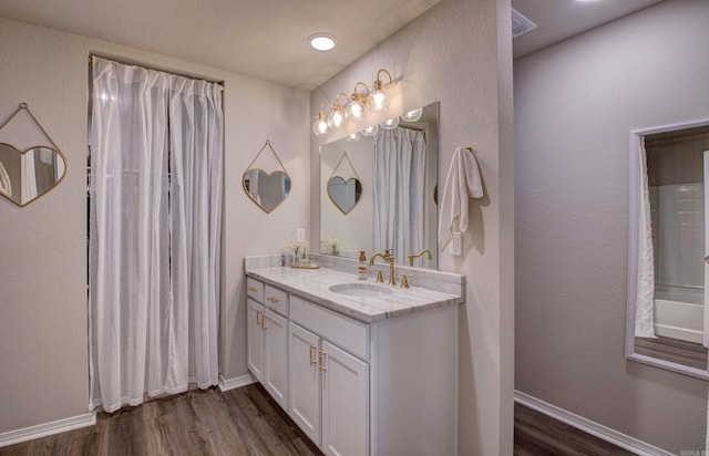 full bath with vanity, baseboards, and wood finished floors