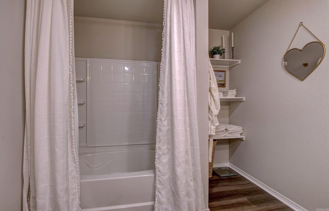 bathroom featuring baseboards, shower / bathtub combination with curtain, and wood finished floors