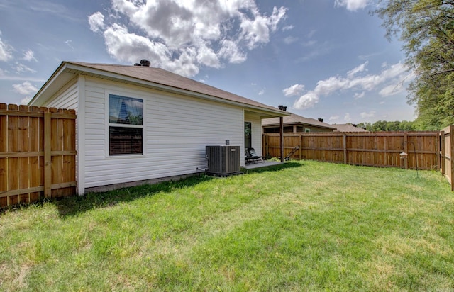 back of property with central air condition unit, a lawn, and a fenced backyard
