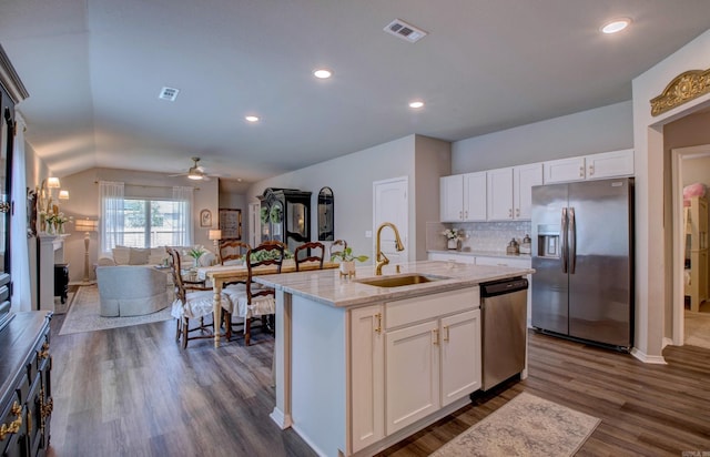 kitchen featuring visible vents, appliances with stainless steel finishes, a sink, white cabinets, and open floor plan