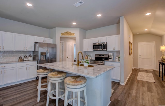 kitchen featuring dark wood-style flooring, a sink, stainless steel appliances, white cabinetry, and visible vents