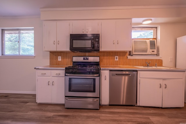 kitchen with wood finished floors, light countertops, white cabinetry, a sink, and stainless steel appliances
