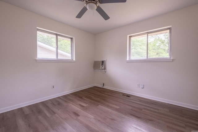 empty room featuring a ceiling fan, baseboards, wood finished floors, visible vents, and a wall mounted AC