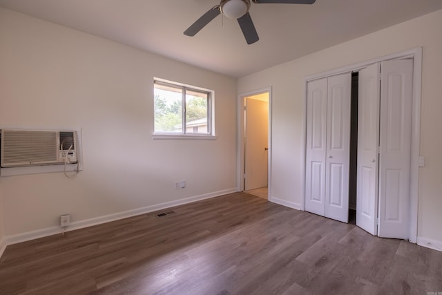 unfurnished bedroom featuring visible vents, a closet, wood finished floors, baseboards, and an AC wall unit