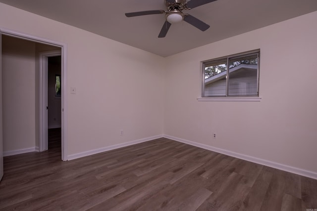 unfurnished room featuring baseboards, dark wood finished floors, and ceiling fan