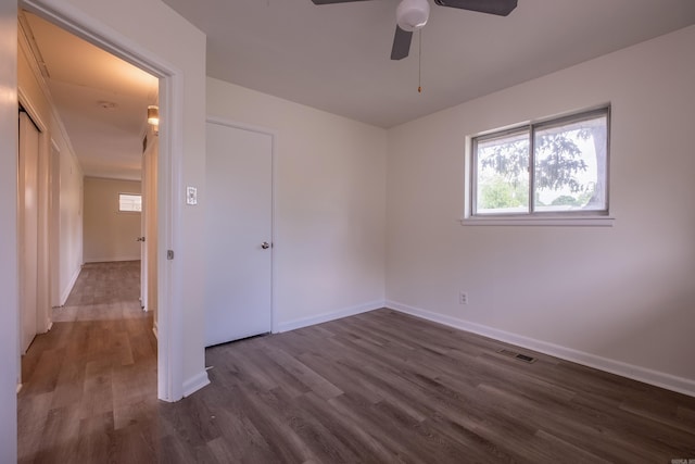 unfurnished bedroom with baseboards, ceiling fan, dark wood-style floors, and visible vents