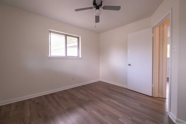 spare room featuring ceiling fan, baseboards, and dark wood-type flooring