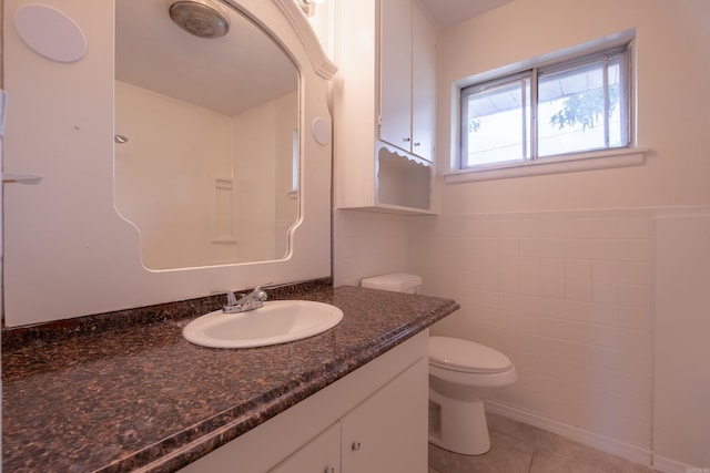 bathroom featuring tile patterned flooring, vanity, toilet, tile walls, and a wainscoted wall