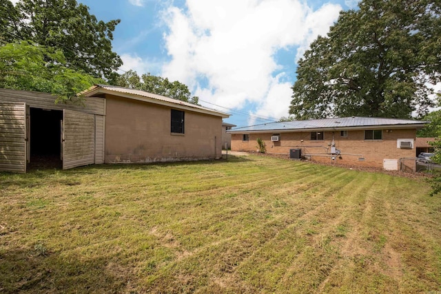 back of house featuring a lawn, concrete block siding, central AC unit, and metal roof