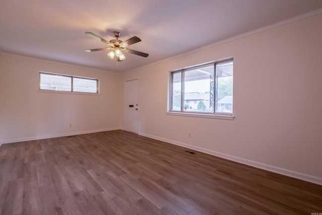 empty room featuring crown molding, ceiling fan, baseboards, wood finished floors, and visible vents