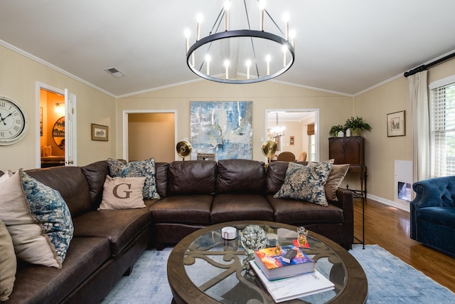 living area with a notable chandelier, ornamental molding, wood finished floors, and vaulted ceiling