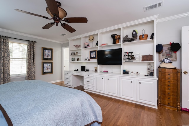 bedroom with crown molding, visible vents, wood finished floors, and built in study area