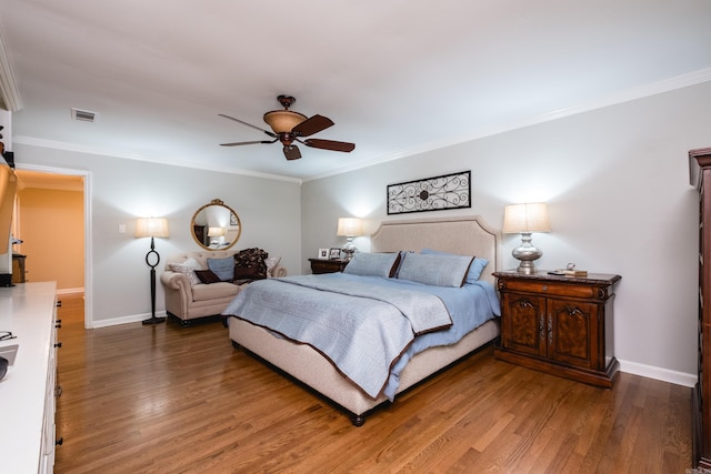 bedroom with a ceiling fan, baseboards, wood finished floors, visible vents, and ornamental molding