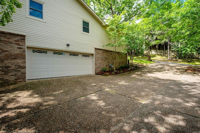 view of property exterior with a garage, concrete driveway, and brick siding