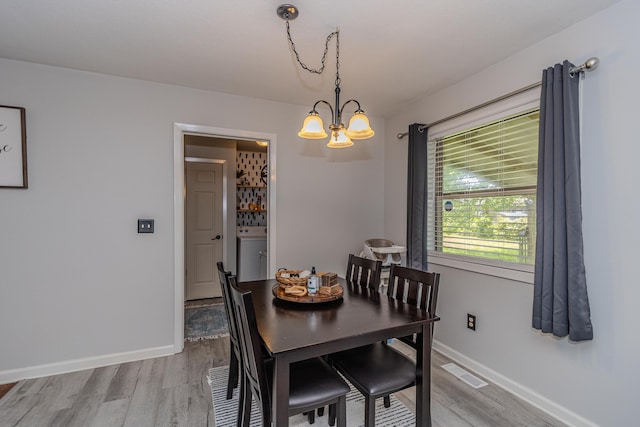 dining area featuring visible vents, washer / dryer, baseboards, a chandelier, and light wood-style flooring