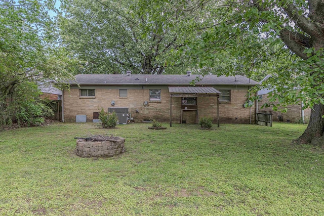 rear view of house with a lawn, fence, and a fire pit
