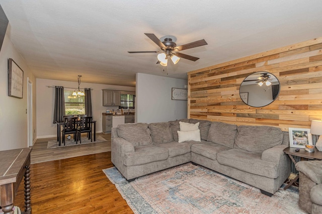 living area with wooden walls, a ceiling fan, and wood finished floors