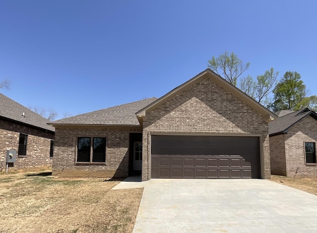 ranch-style home featuring a garage, a shingled roof, driveway, and brick siding