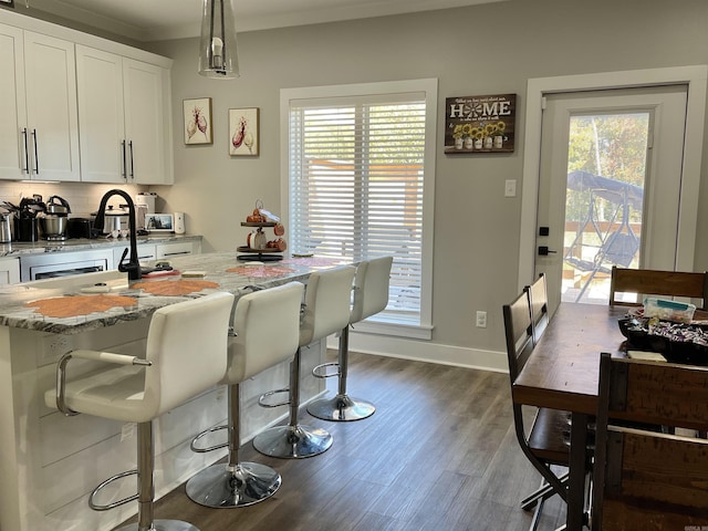kitchen featuring light stone counters, dark wood-style flooring, baseboards, and white cabinets